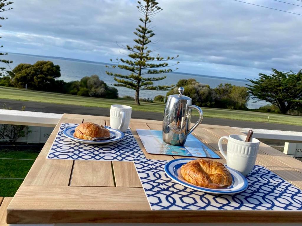 a wooden table with two plates of croissants on it at Baywater in Kingscote