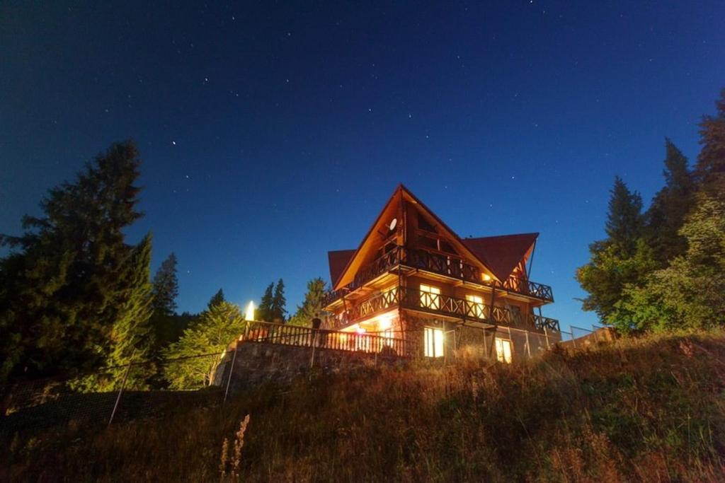 a large house sitting on top of a hill at night at Casa del Pozitiff in Slavske