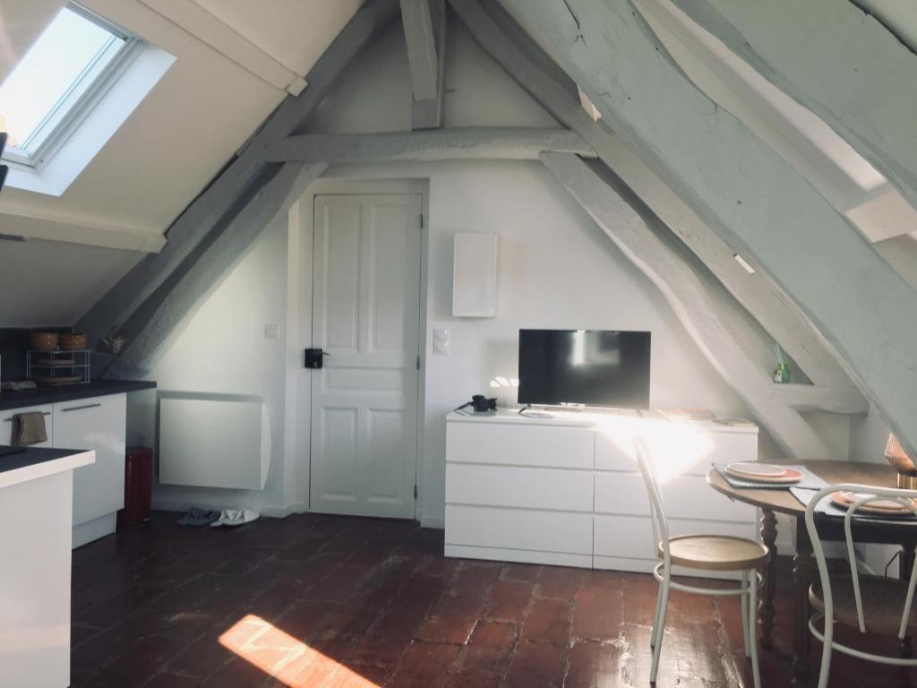 Zimmer im Dachgeschoss mit einem Tisch und einem TV in der Unterkunft TONNERRE grand studio de charme au coeur de la ville in Tonnerre
