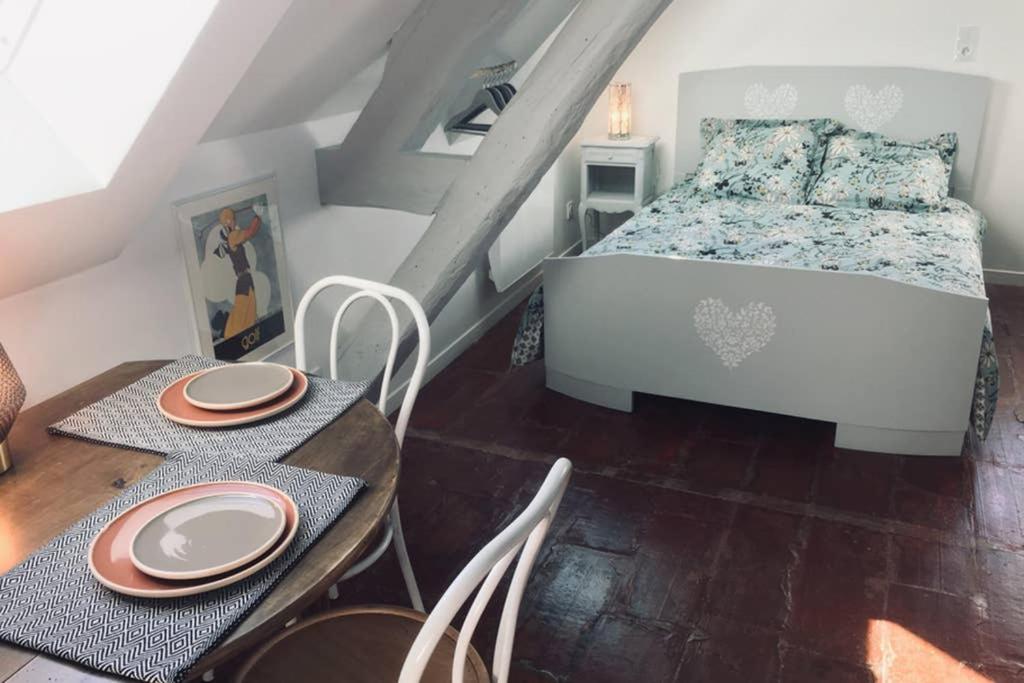 une chambre avec un lit, une table et des chaises dans l'établissement TONNERRE grand studio de charme au coeur de la ville, à Tonnerre