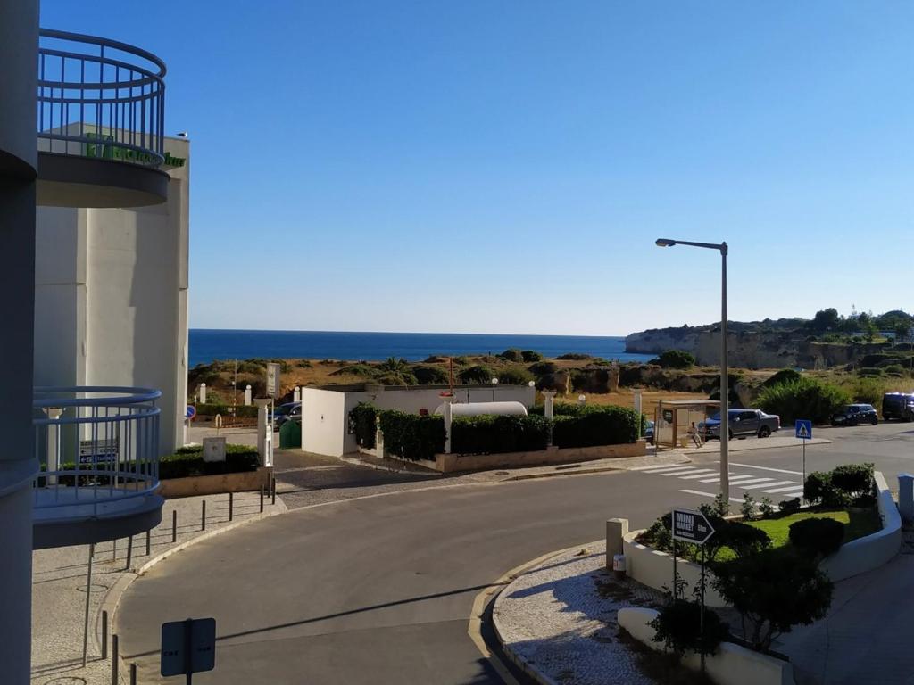 an empty street in front of a building with the ocean at 1A Atlantico - Casas & Papeis in Armação de Pêra