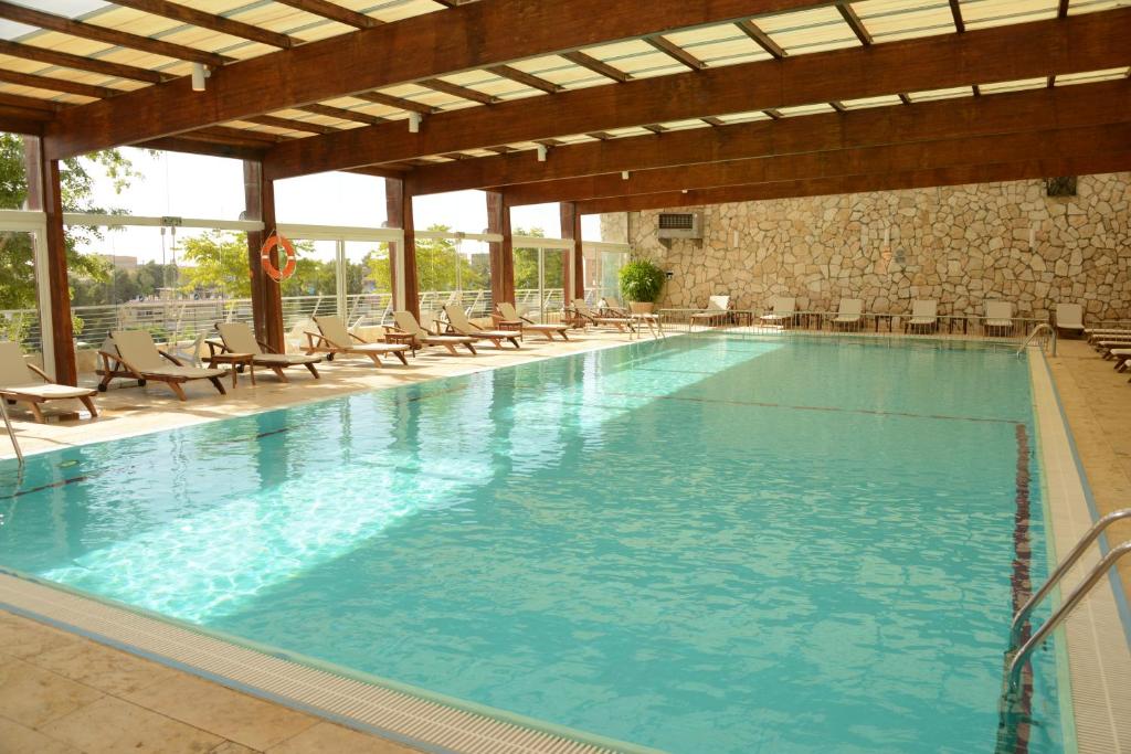 a large swimming pool with chairs in a building at Ramon Inn by Isrotel Collection in Mitzpe Ramon