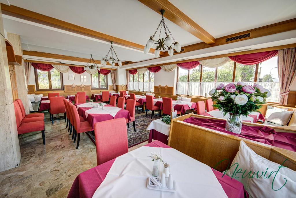 um restaurante com mesas, cadeiras vermelhas e flores em Gasthof Neuwirt / Kressnig em Klagenfurt