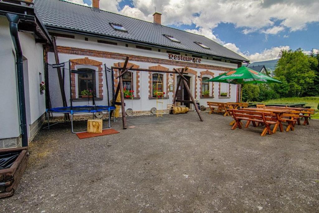 ein Gebäude mit Picknicktischen und einem grünen Regenschirm in der Unterkunft Pension U Mojmíra in Rokytnice nad Jizerou