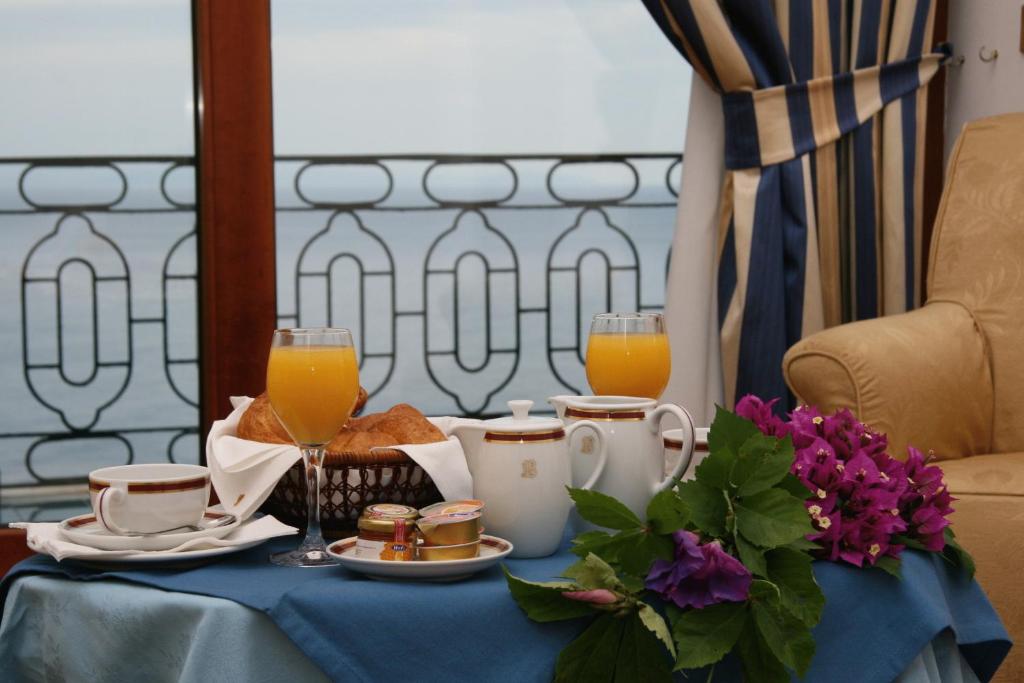 a table with a breakfast of orange juice and toast at Hotel Belvedere in Conca dei Marini