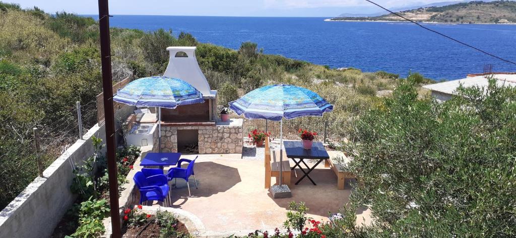 two blue chairs and umbrellas on a patio near the ocean at Apartment Erjon in Ksamil