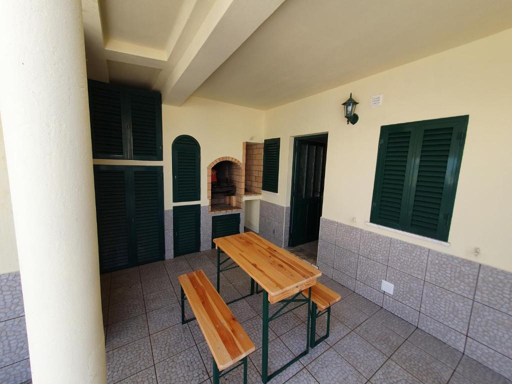 une table et deux bancs sur une terrasse couverte avec volets verts dans l'établissement Algarve Villa Albufeira Altos dos Caliços, à Albufeira