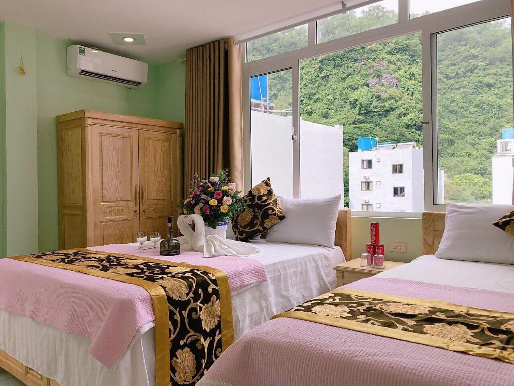 two beds in a room with a large window at Green Mountain Hostel in Cat Ba