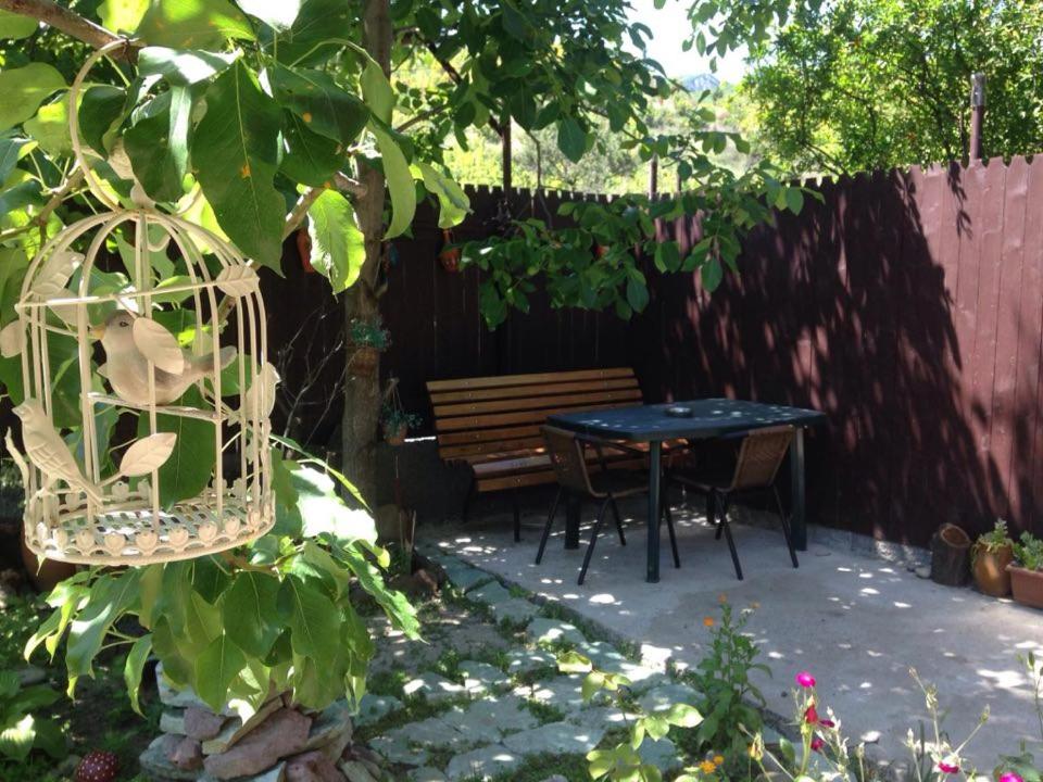 a patio with a table and a bench in a garden at Niki in Mtskheta