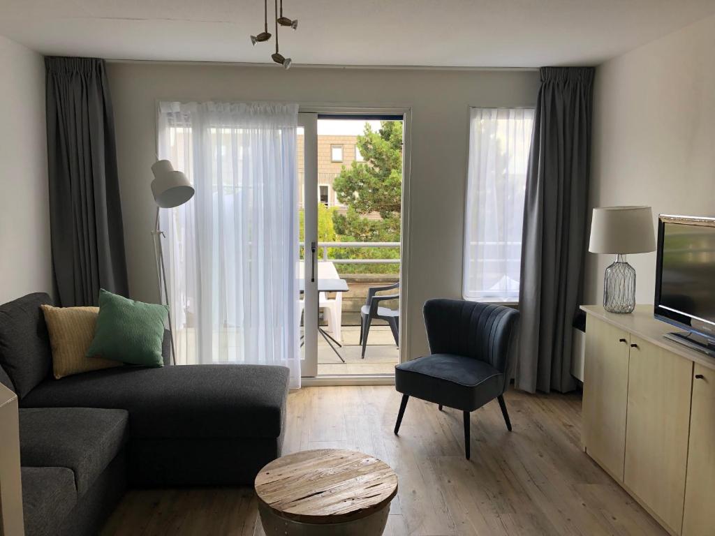 een woonkamer met een bank, een stoel en een televisie bij Appartement Waddengeluk Resort Amelander Kaap! in Hollum