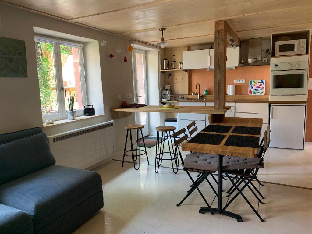 eine Küche und ein Wohnzimmer mit einem Tisch und Stühlen in der Unterkunft Gîte Côté Verre in Meisenthal
