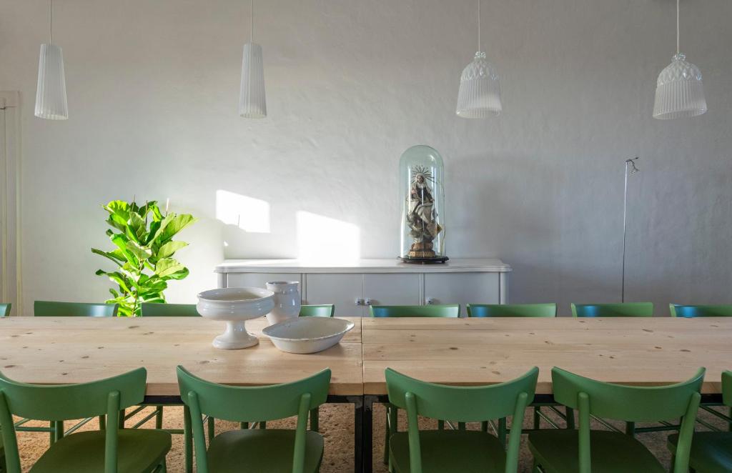 uma sala de jantar com uma mesa de madeira e cadeiras verdes em Galeta Masseria em Nardò