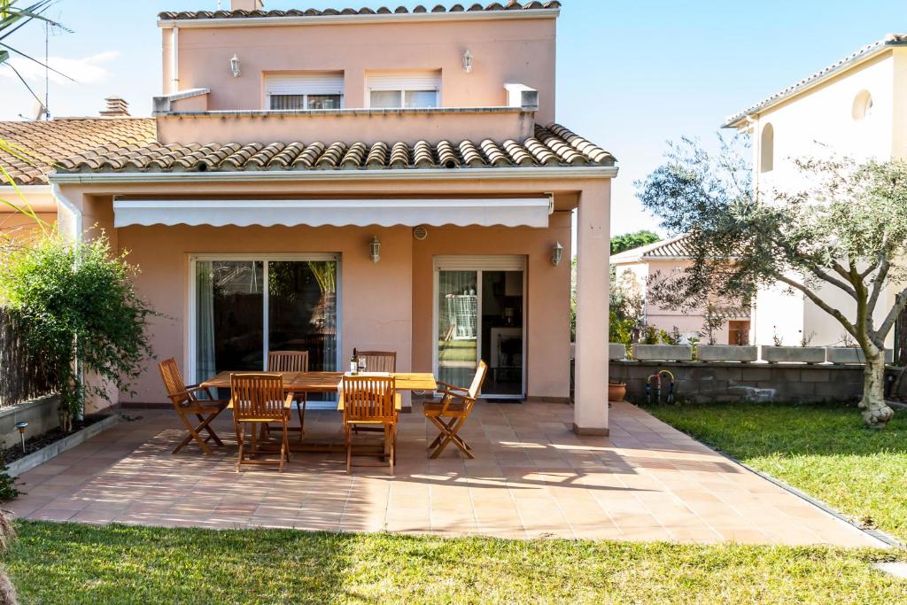 a patio with a table and chairs in front of a house at CASA CON JARDIN-WIFI FREE in L'Escala