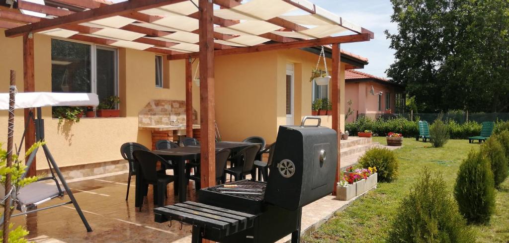 patio con tavolo e sedie sotto un pergolato di Vyara Holiday Home a Krapets