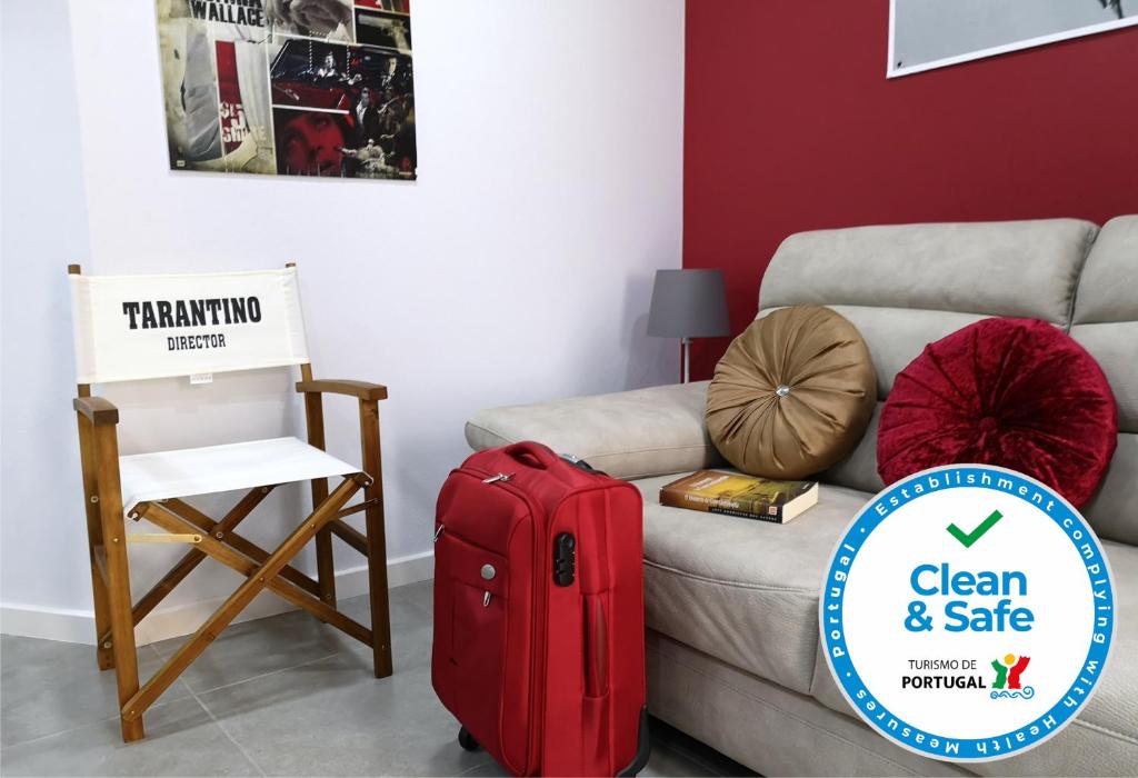 a red suitcase sitting next to a couch with a chair at Vila Maior in Sertã