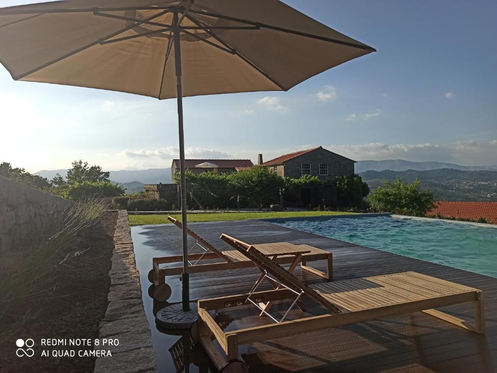 uma piscina com uma mesa e um guarda-sol ao lado de uma piscina em Quinta do Caritel em Vouzela