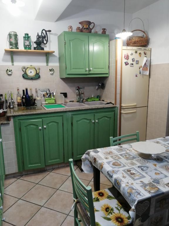 kuchnia z zielonymi szafkami, stołem i lodówką w obiekcie IL CASOTTO w mieście Itri
