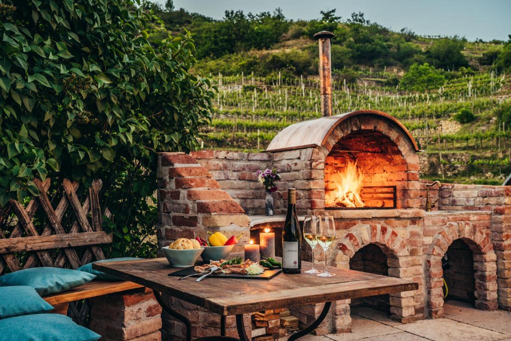 einen SteinPizzaofen mit einem Tisch mit Speisen und Wein in der Unterkunft Wachau-Living in Dürnstein