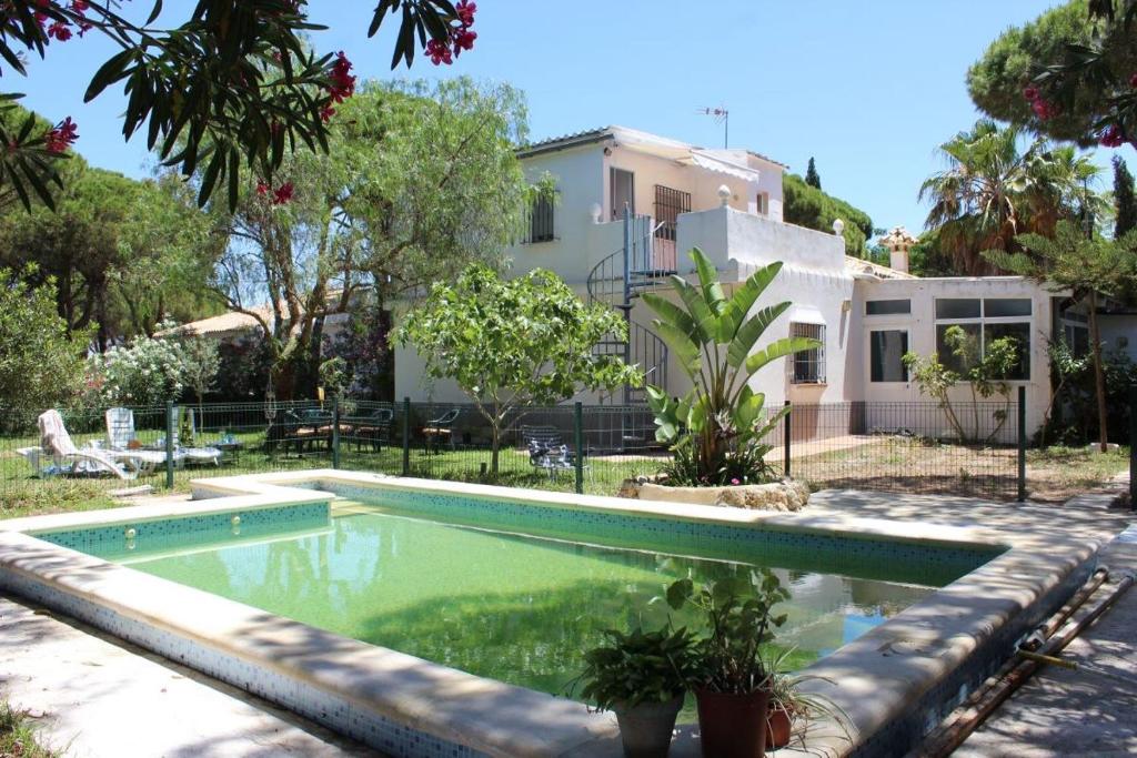 a swimming pool in front of a house at Villa andaluza en zona Playa Barrosa con piscina y barbacoa in Chiclana de la Frontera