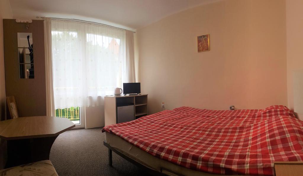a bedroom with a bed with a red plaid blanket at pokoje STIFADO in Międzyzdroje