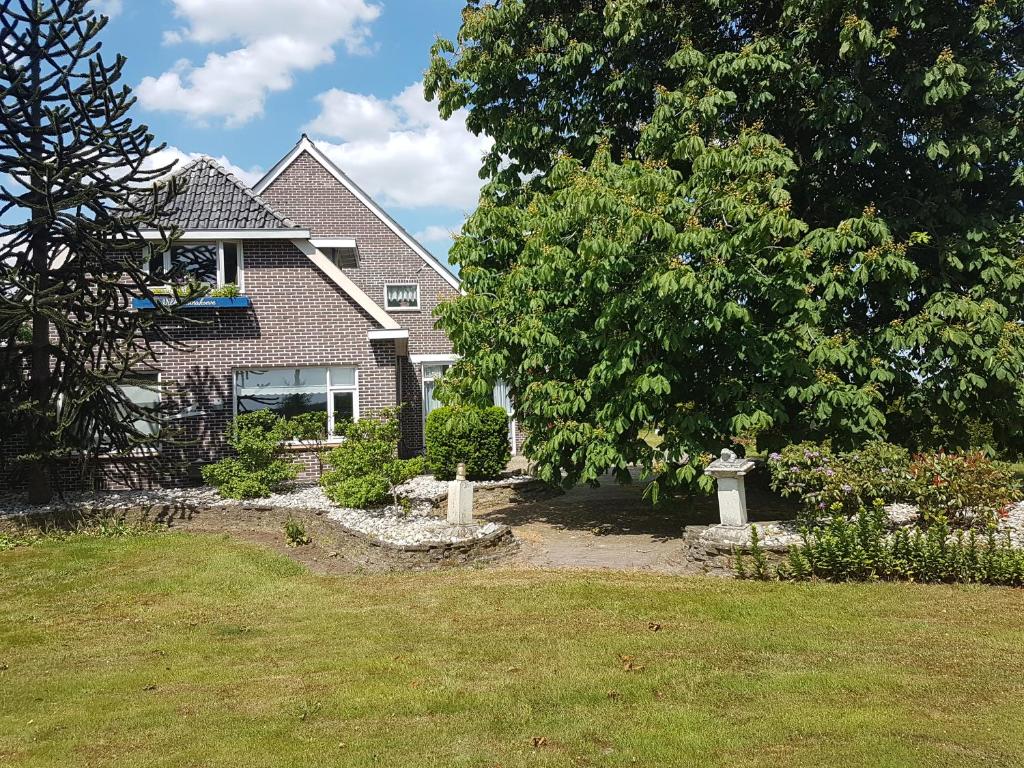 una casa con un patio con un árbol y césped en Wilhelminahoeve, en Tiendeveen