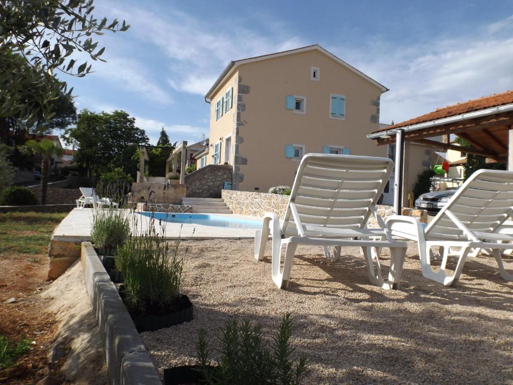 eine Gruppe weißer Stühle neben einem Pool in der Unterkunft Apartment Marina Kornić in Kornić