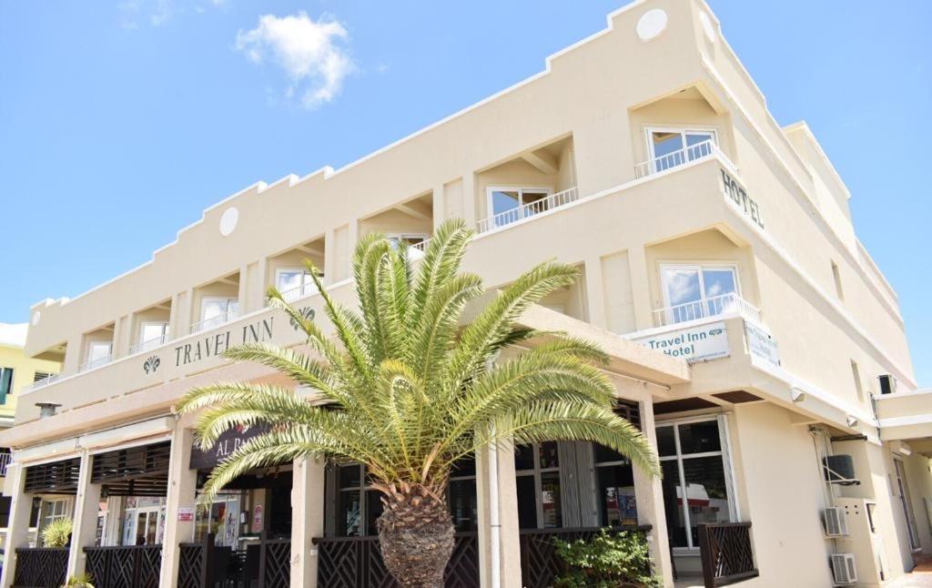 um edifício com uma palmeira em frente em Travel Inn Hotel Simpson Bay em Simpson Bay