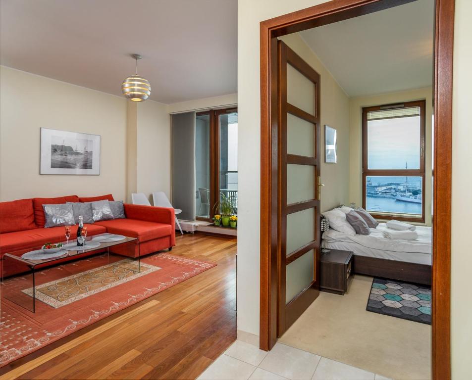 a living room with a red couch and a table at Sea Towers "Sweet Dream" in Gdynia