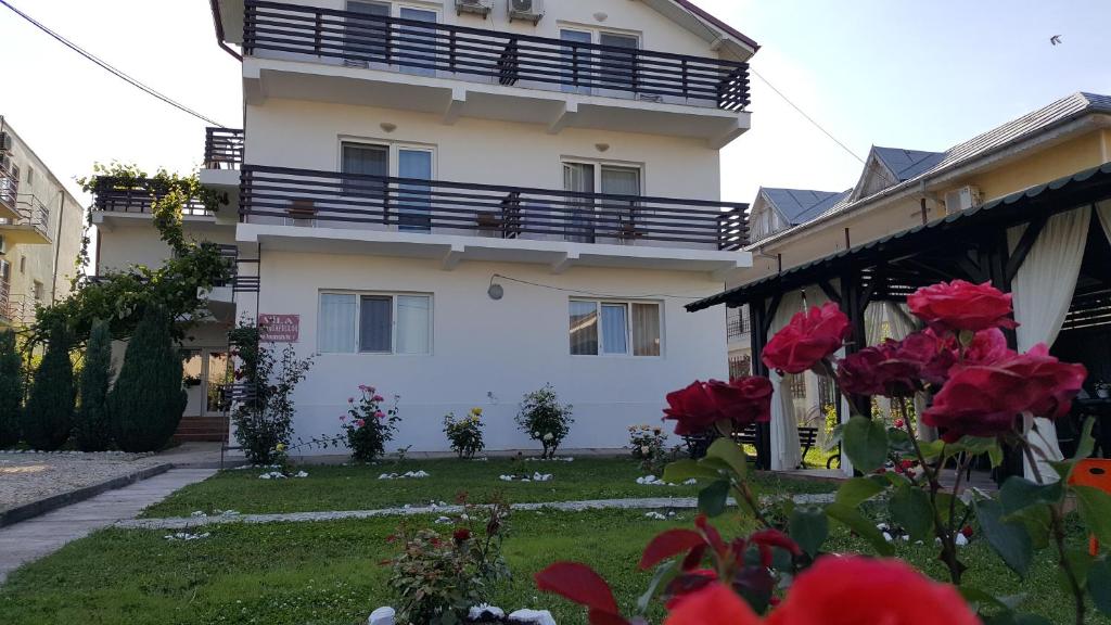 Vila Trandafirilor Costinești في كوستينيشت: مبنى أبيض مع شرفة وورد احمر