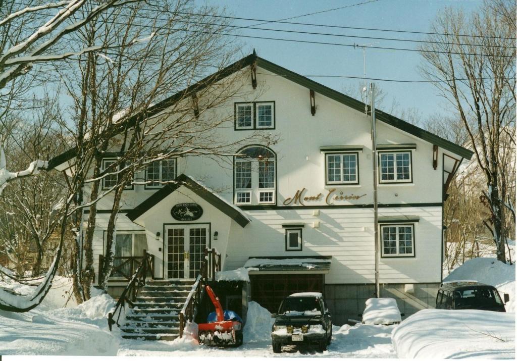 Une grande maison blanche avec de la neige au sol dans l'établissement Mont Cervin, à Myōkō