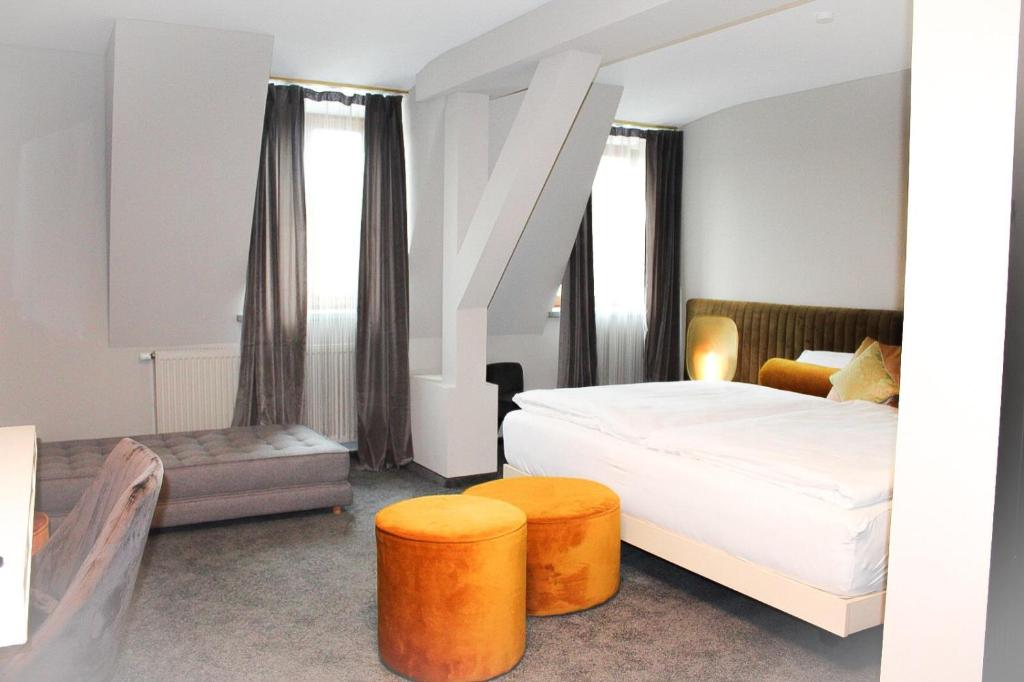 1 dormitorio con 1 cama y 2 taburetes de color naranja en Hotel Krumbach en Krumbach