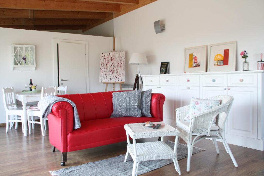 ein Wohnzimmer mit einem roten Sofa und weißen Stühlen in der Unterkunft Cottage Gols in Gols