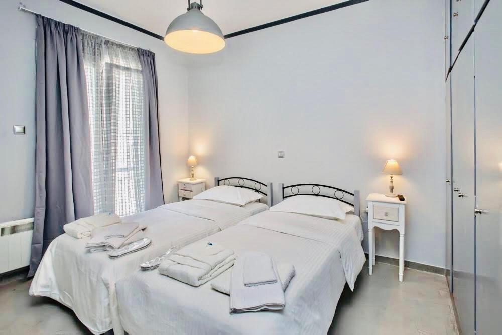 1 dormitorio blanco con 2 camas y ventana en Cozy flat in Tinos, en Tinos