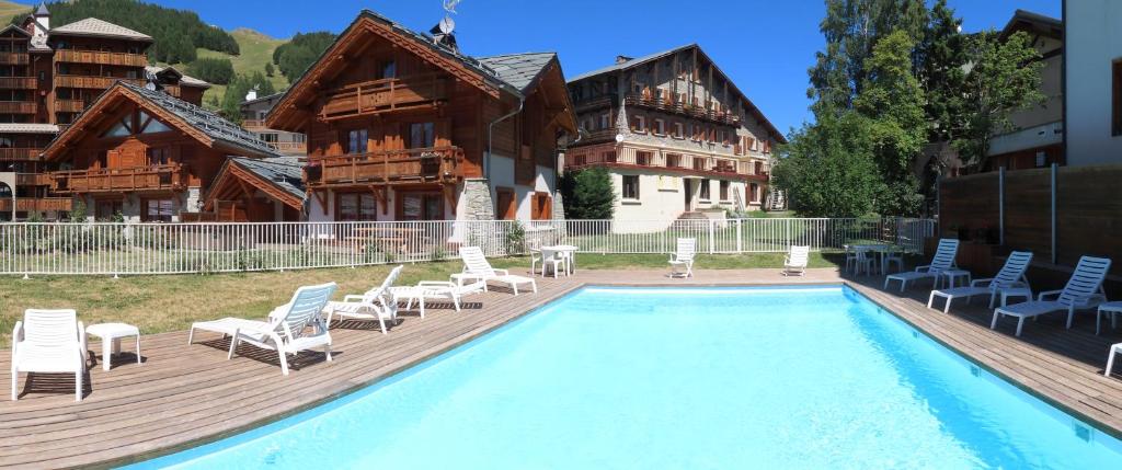 una piscina frente a una casa con sillas y un edificio en La Belle Etoile, en Les Deux Alpes