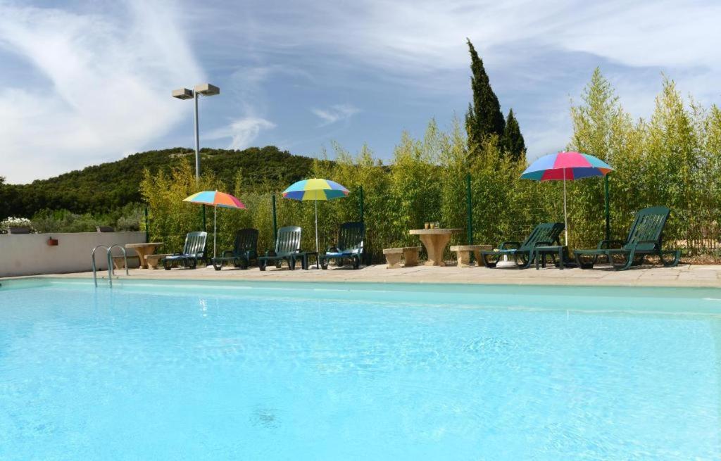 uma piscina com cadeiras e guarda-sóis em Hotel Le Lagon em Rochefort-du-Gard