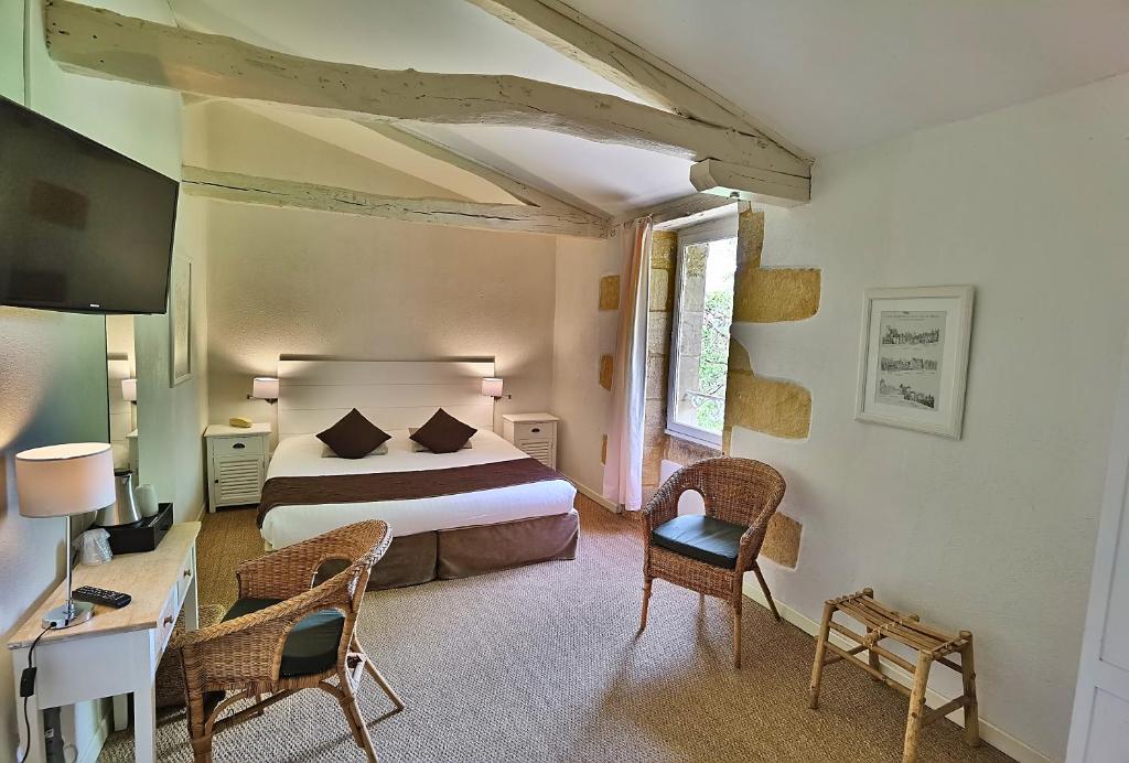 a bedroom with a bed and a desk and chairs at Hotel La Maison des Peyrat in Sarlat-la-Canéda