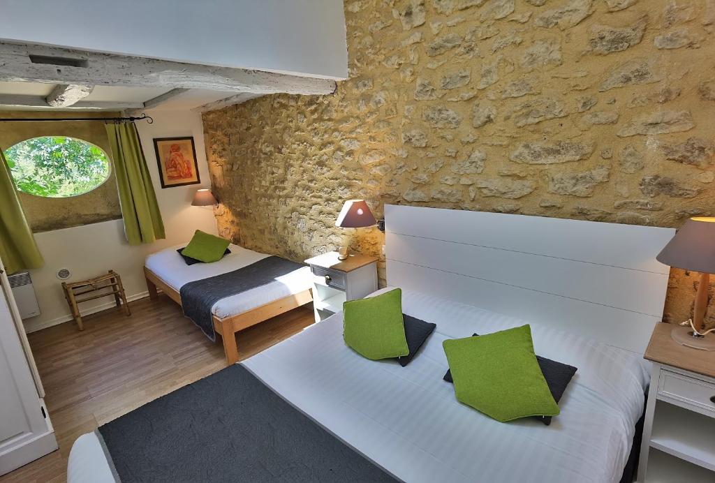 a bedroom with two beds and a stone wall at Hotel La Maison des Peyrat in Sarlat-la-Canéda