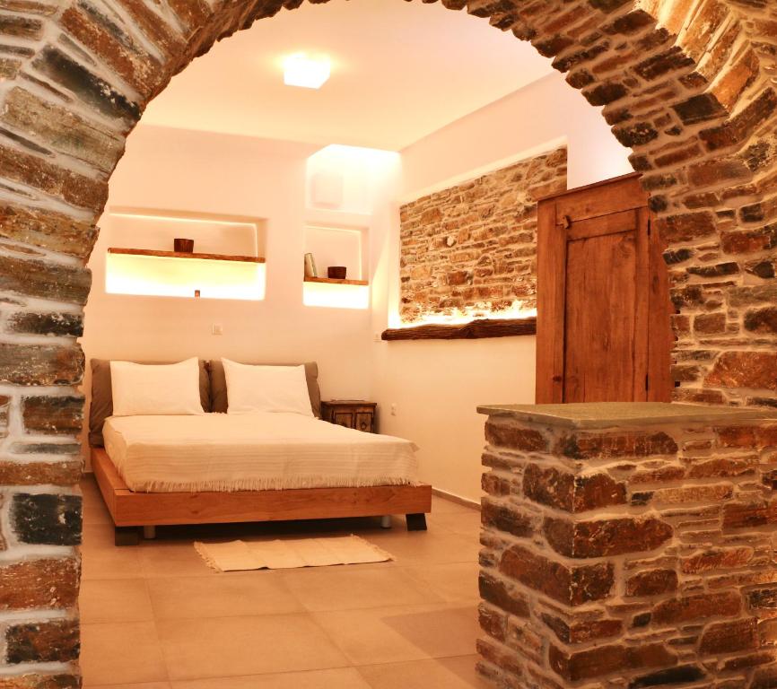 a bedroom with a bed and a brick wall at Kounelia Luxury Apartments in Kithnos