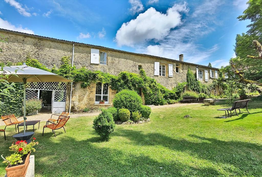 une maison avec une cour dotée de chaises et d'un parasol dans l'établissement Hotel La Maison des Peyrat, à Sarlat-la-Canéda