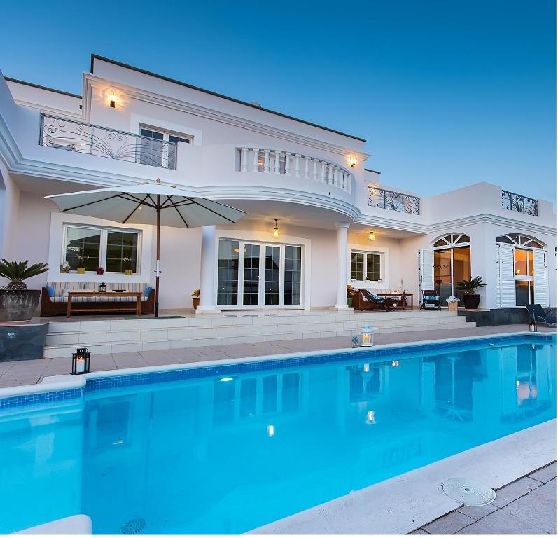 a large swimming pool in front of a house at Villa Costa Golf in Costa Teguise