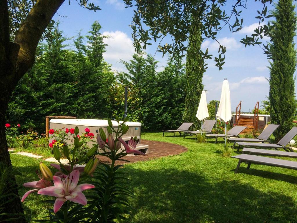 un giardino con panchine, fiori e ombrelloni di Agriturismo Al Tralcio a Valeggio sul Mincio