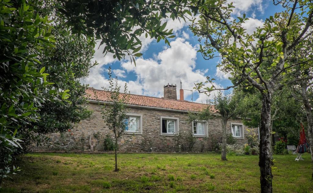 una vista exterior de una casa de piedra con árboles en Turismo Rural O Xastre de Anos en Cabana de Bergantiños