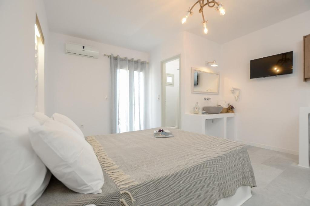 a white room with a bed and a tv at Casa Verde Di Naxos in Naxos Chora