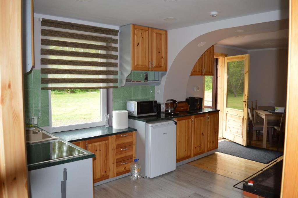 cocina con armarios de madera, fregadero y ventana en Piepilsēta en Alūksne