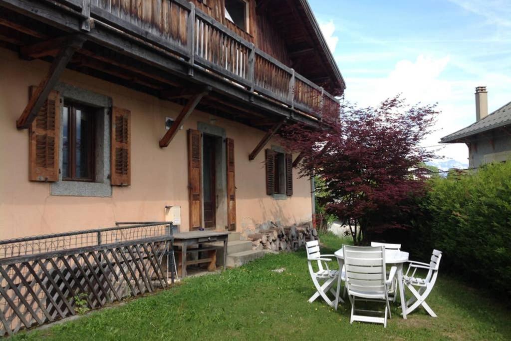 uma mesa e cadeiras em frente a uma casa em Appartement spacieux proche des télécabines et du centre ville avec jardin privé em Saint-Gervais-les-Bains