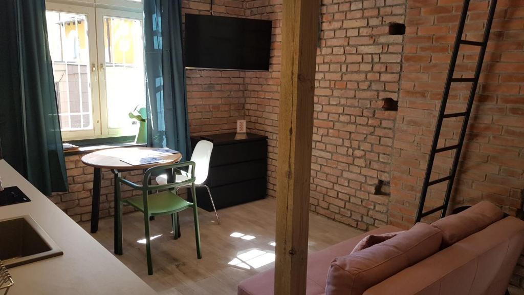 a living room with a couch and a table and a brick wall at StudioSpanie Art Studio II in Sopot