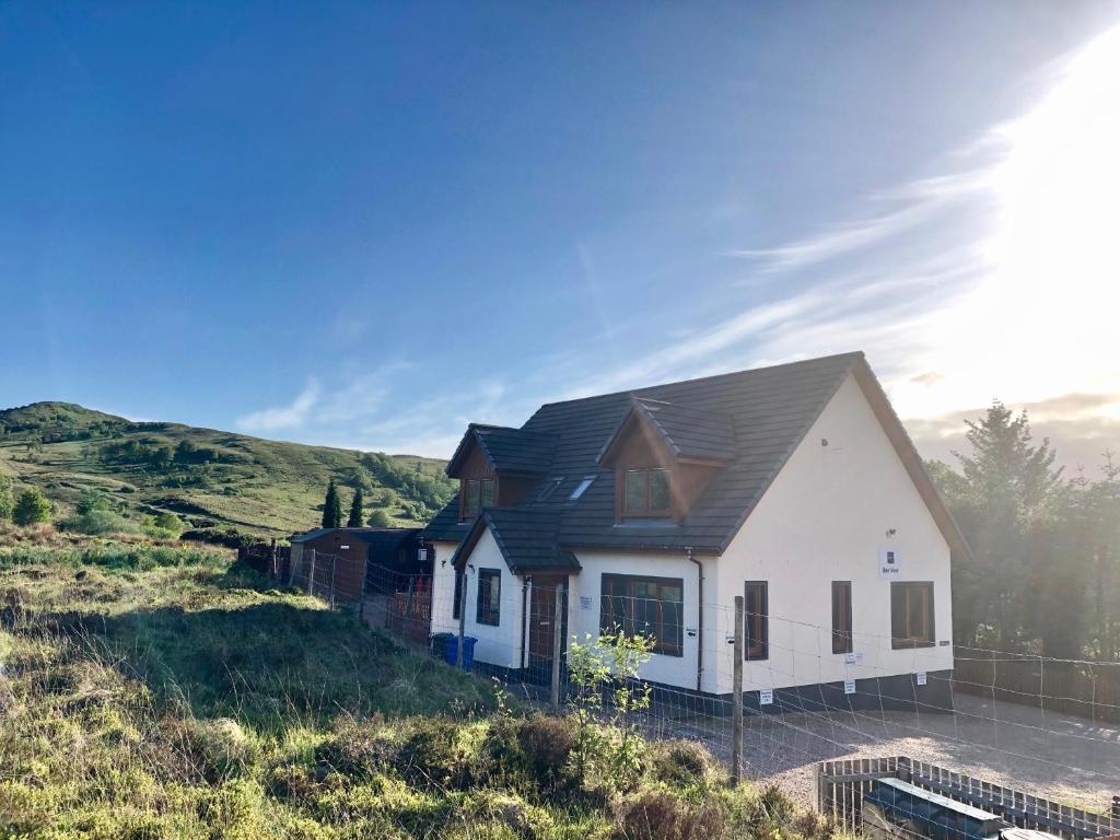 a white house with a black roof on a hill at Highland Stays - Ben View Double Rooms in Fort William