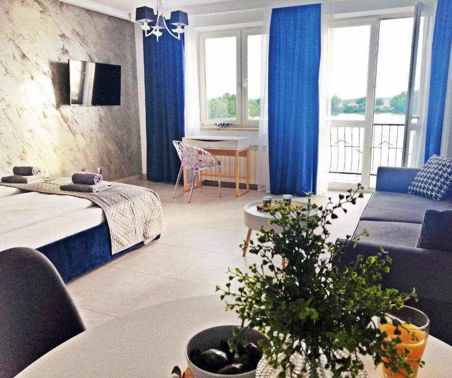 a living room with blue curtains and a bed and a table at Apartamenty Na Skarpie in Ełk
