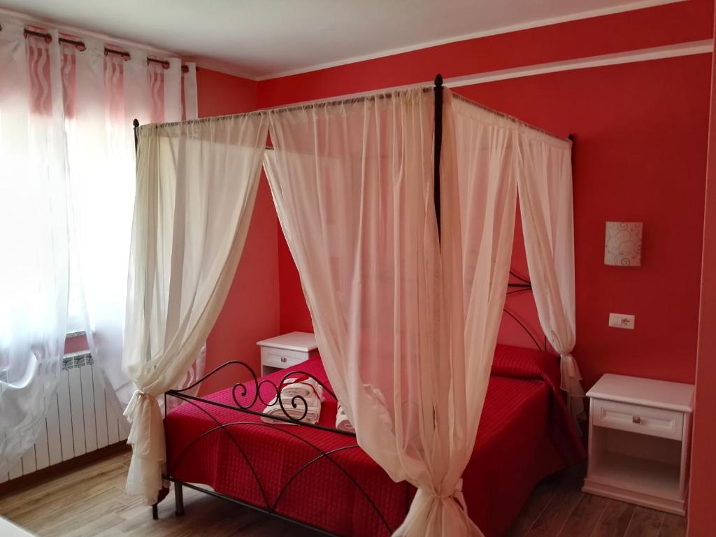 a bedroom with red walls and a bed with a canopy at Nel verde di Carinci in Castelpetroso