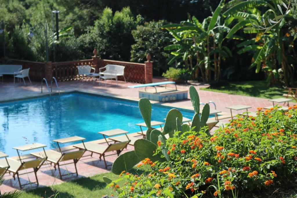 a swimming pool with chairs and a table and a table and chairsitures at Villa delle Palme in Acitrezza